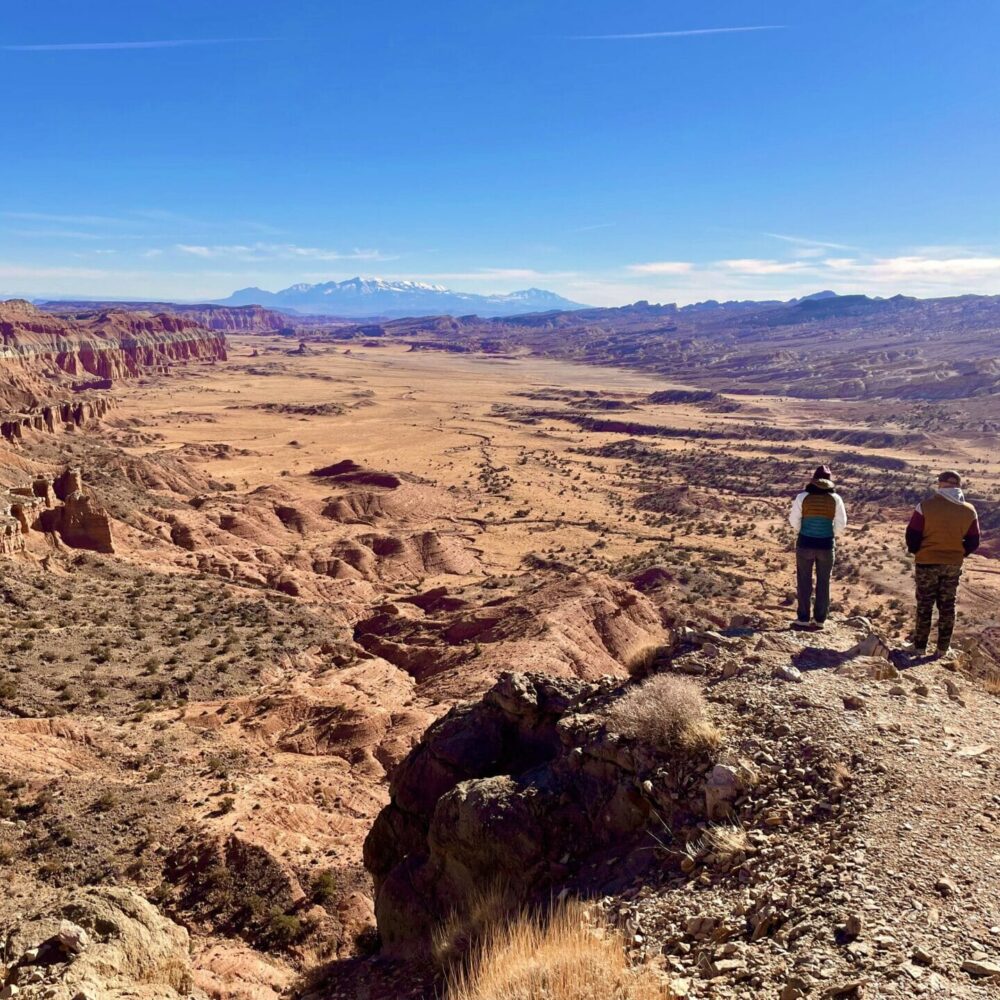 couple looking over cliff edge at upper south desert overlook, capitol reef national park, utah