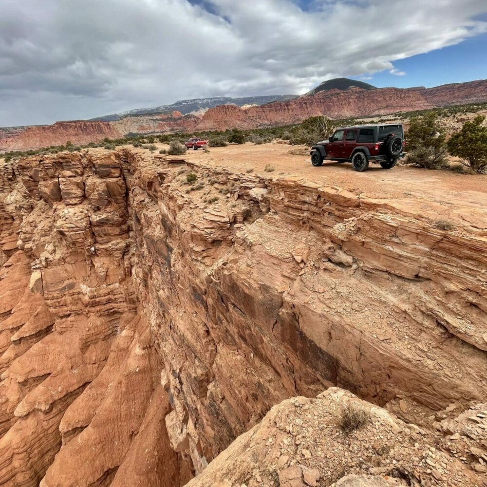 dark red jeep parked on cliff edge