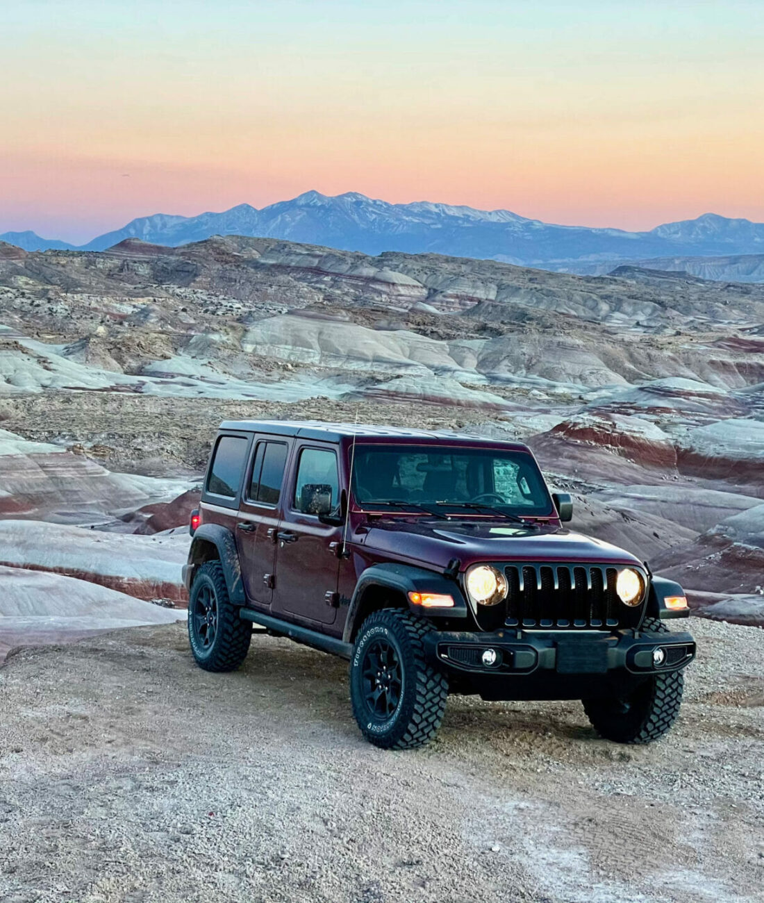 dark red jeep sitting on a bentonite hill