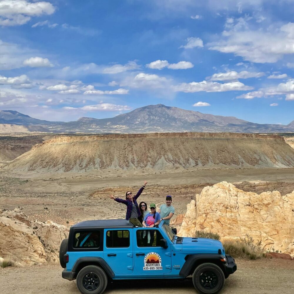 Girls sitting on jeep on side of cliff, driving the burr trail switchbacks inside capitol reef national park