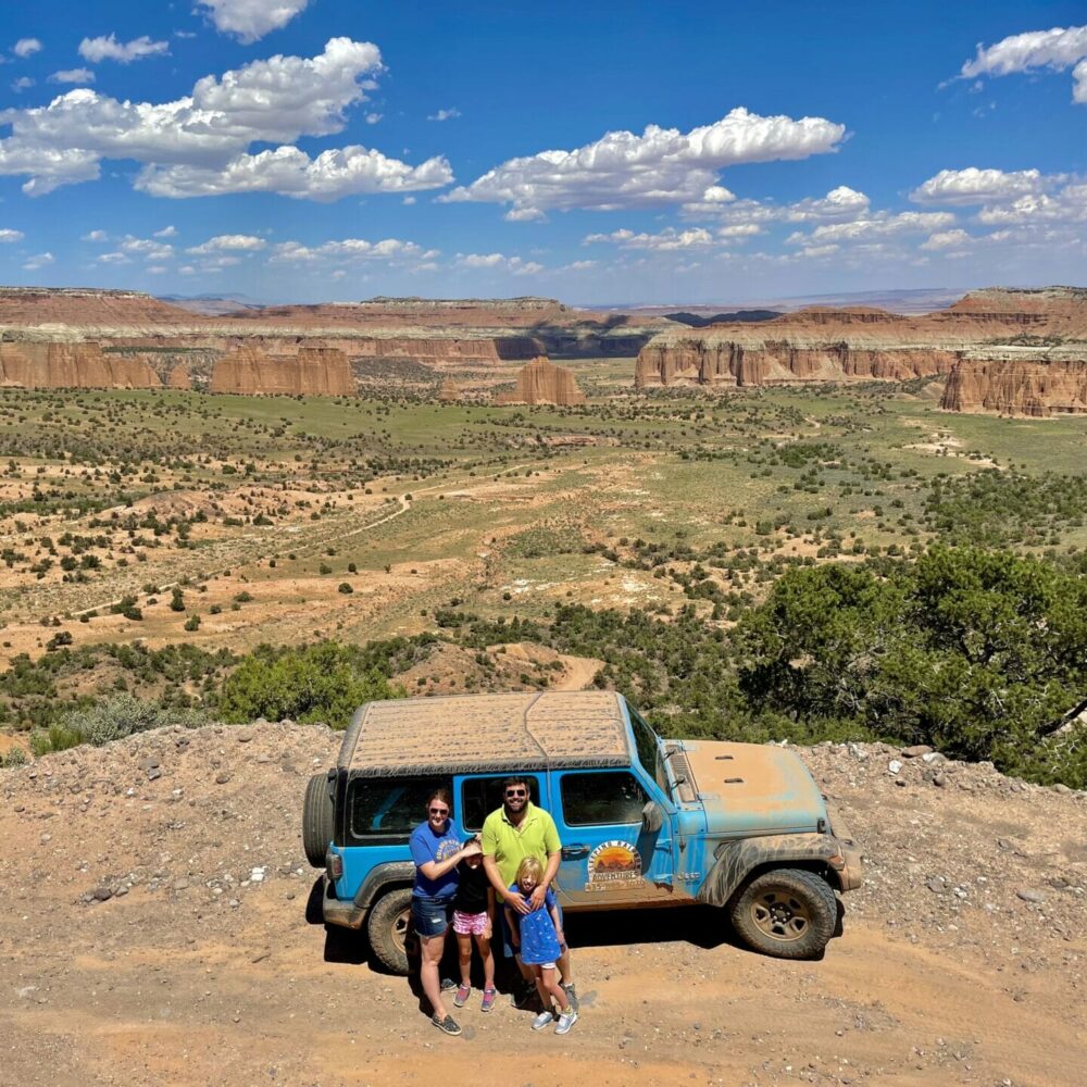 family posing in front of muddy jeep, over the upper cathedral valley