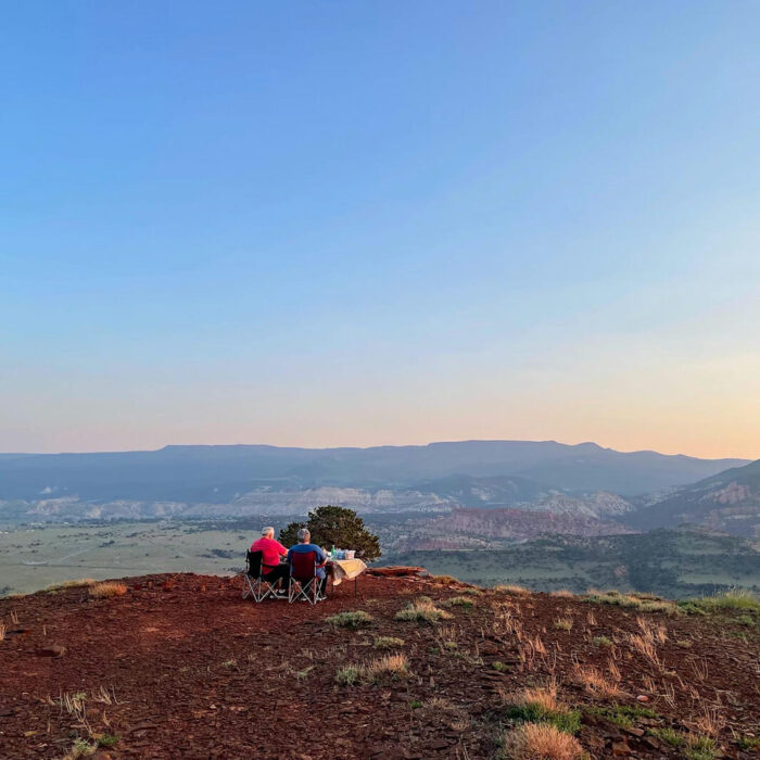couple having picnic on cliff edge during sunset, at the velvet ridge, utah